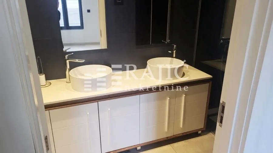 Modernly equipped bathroom with dual washbasins and white cabinetry.