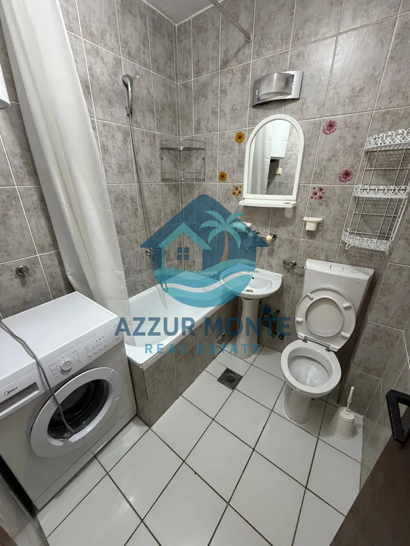 Smaller bathroom with a bathtub, washbasin, toilet, and washing machine.