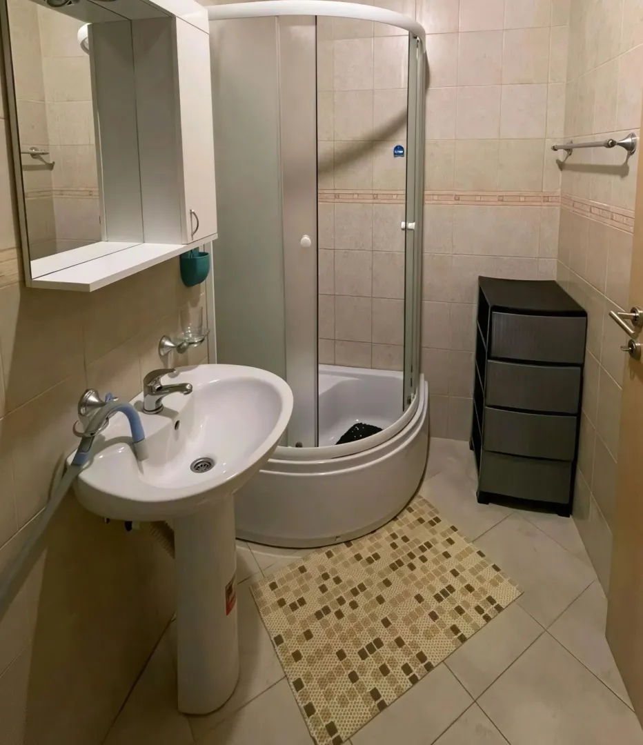 Manje kupatilo sa umivaonikom, tuš kabinom i ormarićem.