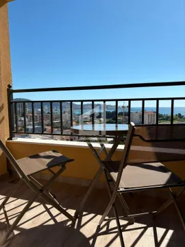 Furnished terrace with a table and two chairs and a view of the city and the sea. - image 2