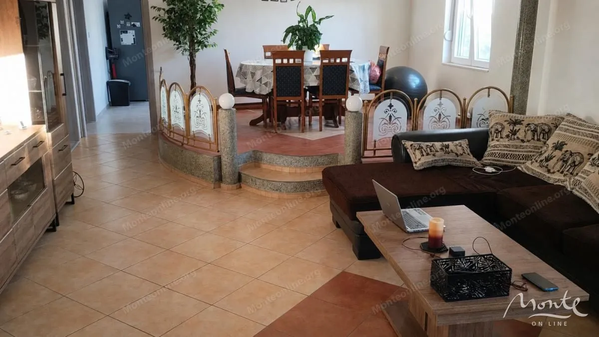 Dnevna soba sa garniturom i trpezarijom u pozadini.