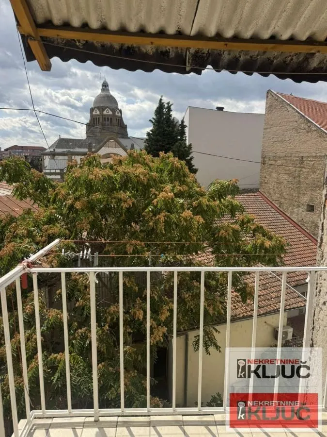 Pogled sa balkona na okolne zgrade i gradsku arhitekturu.