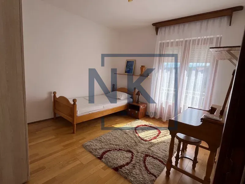 Spavaća soba sa drvenim krevetom, radnim stolom i tepihom.