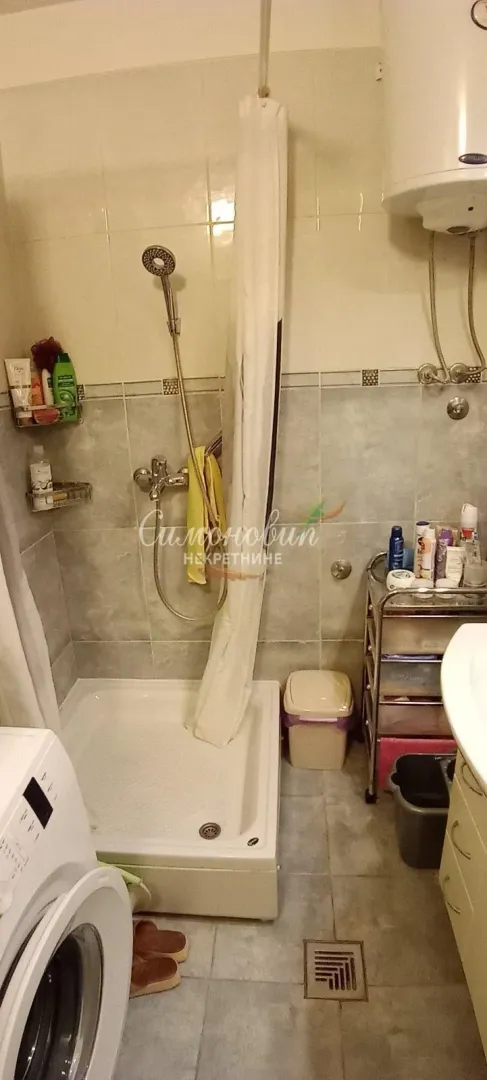 Manje kupatilo sa tuš kabinom, umivaonikom i veš mašinom.