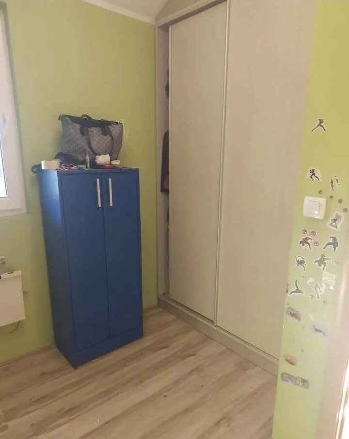 Manja spavaća soba sa ugradnim ormarom i plavim elementom.