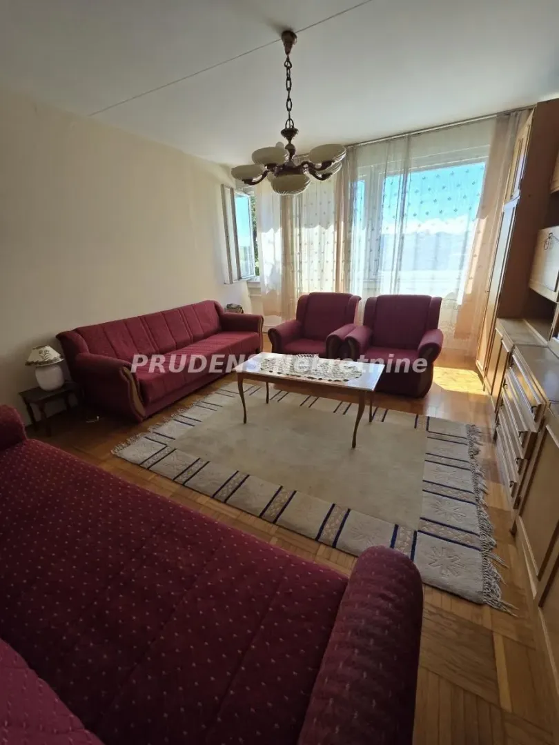 Dnevna soba sa garniturom za sedenje i drvenim nameštajem.