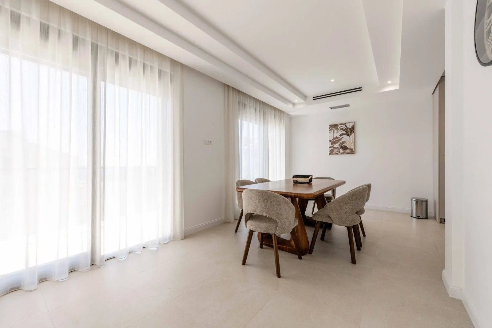 Spacious dining area with a wooden table and chairs next to large glass doors.