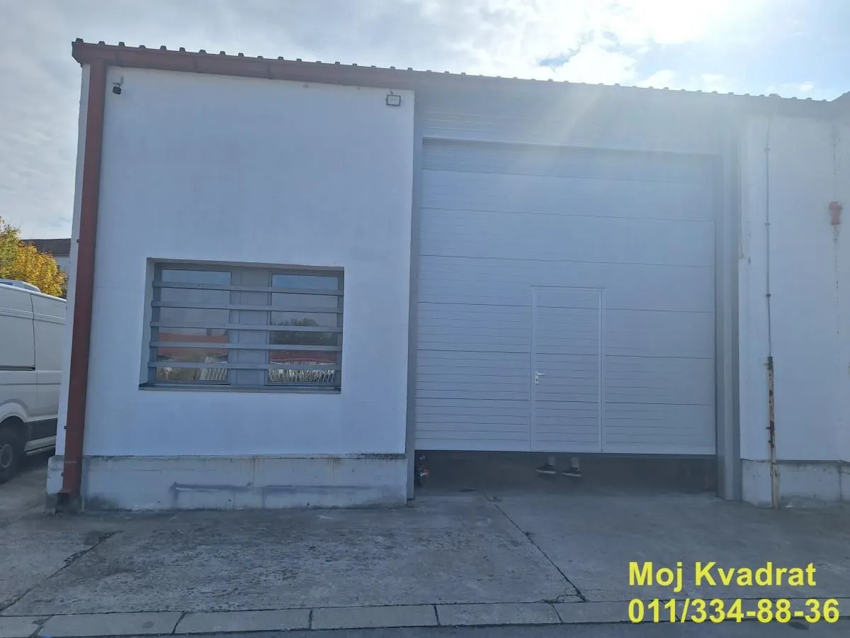 Exterior view of the industrial building with a roll-up door and a window.