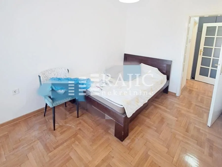Furnished bedroom with a double bed and parquet flooring.
