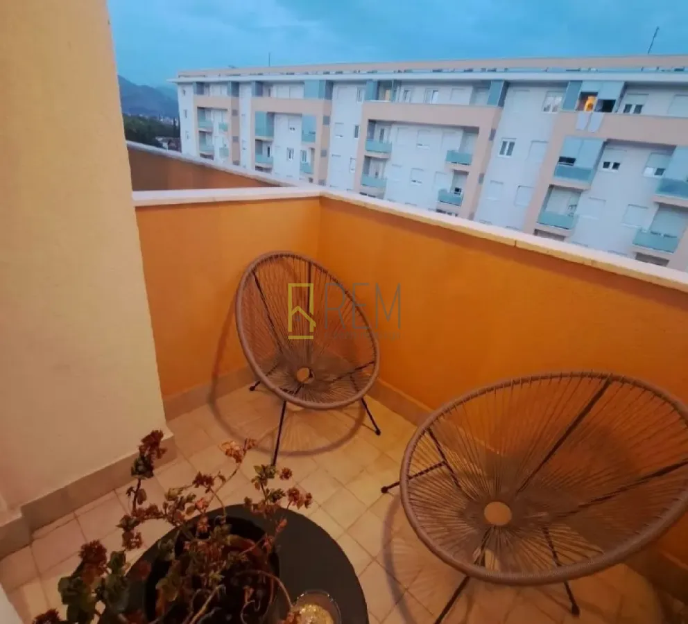 Manji namješten balkon sa dvije stolice i pogledom na zgradu.