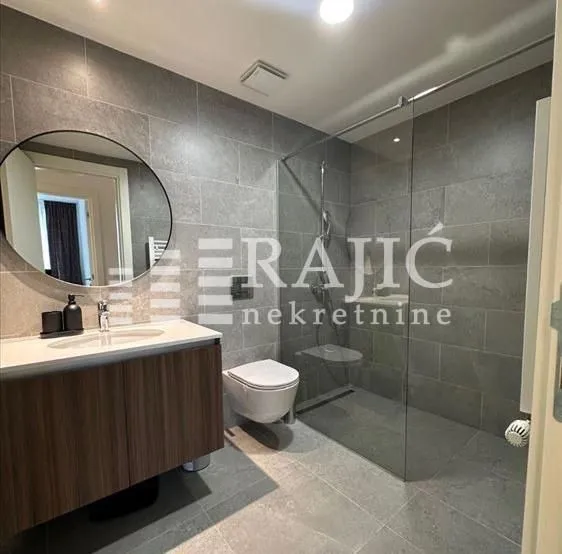 Modern bathroom with a walk-in shower, vanity sink, and mirror.