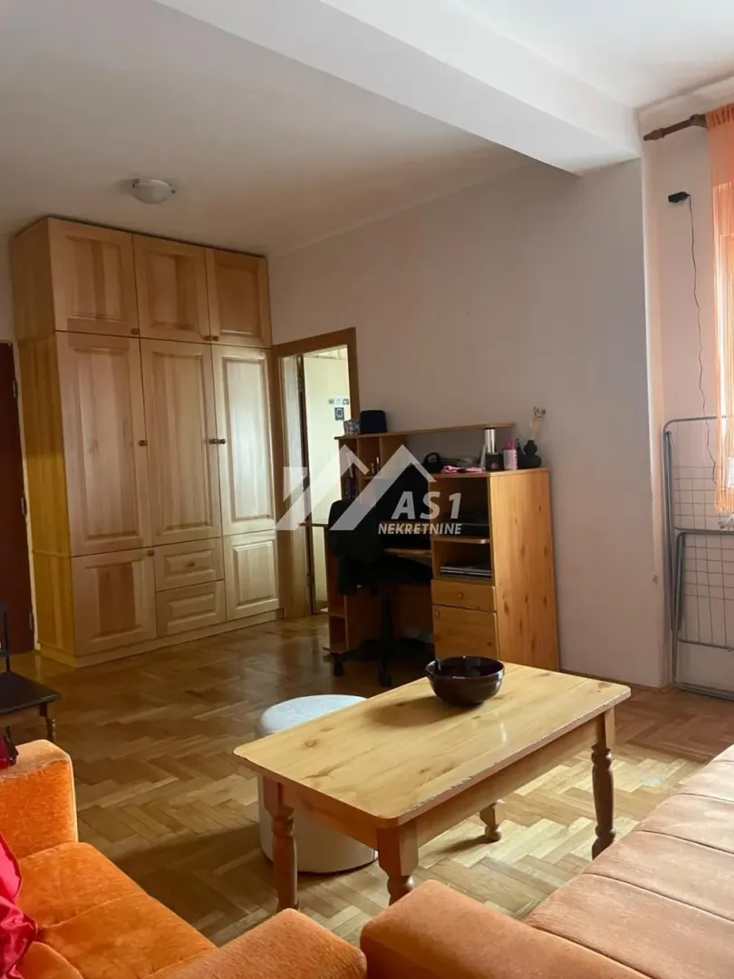 Dnevna soba sa drvenim nameštajem i parketom na podu.