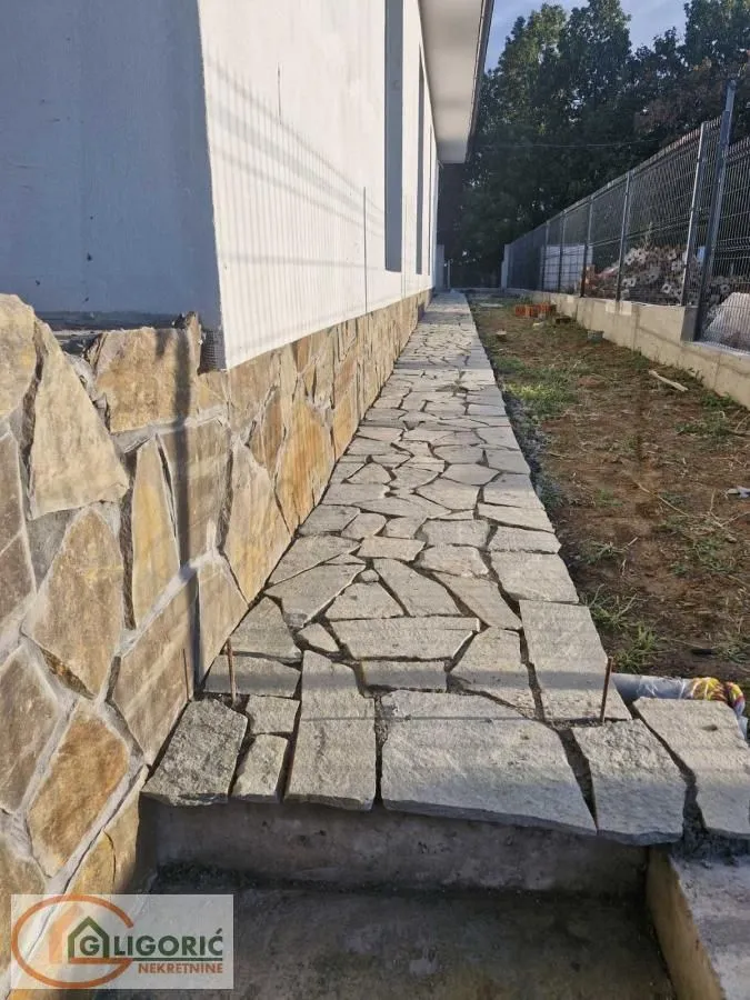 Pogled na popločanu stazu i dvorište pored kuće.