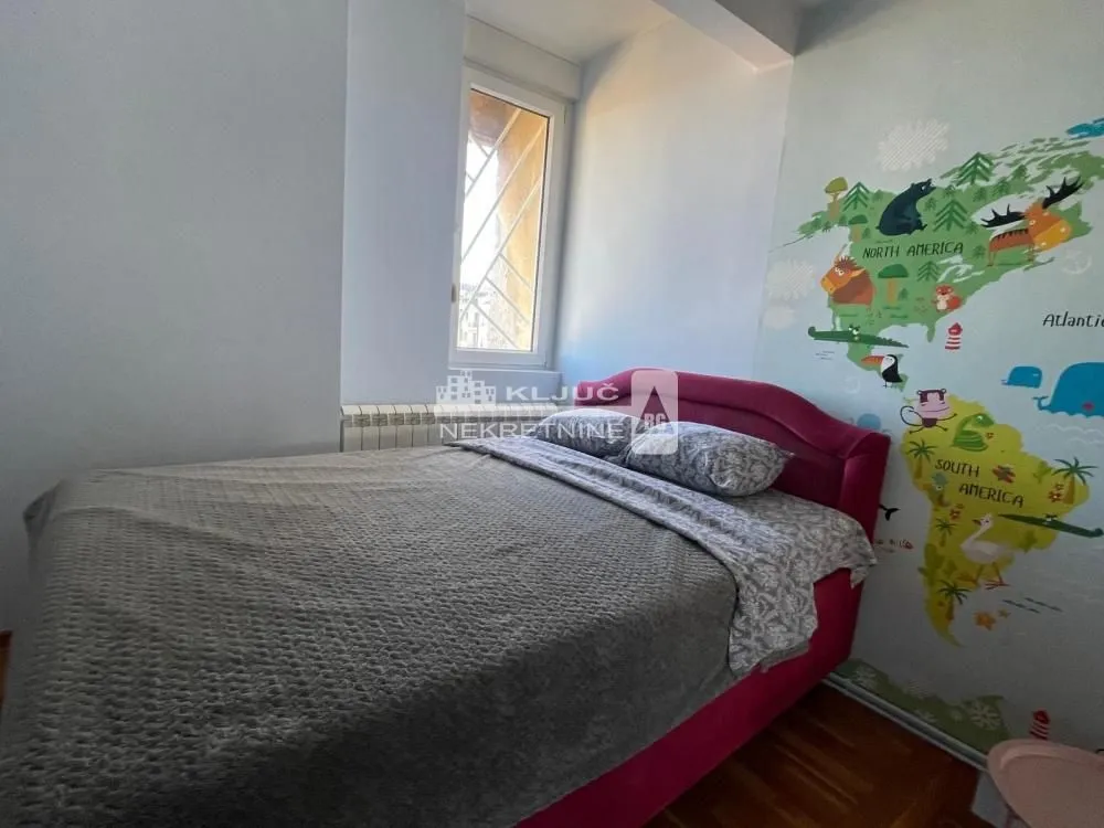 Dečja spavaća soba sa krevetom i tapetom sa motivom mape sveta.