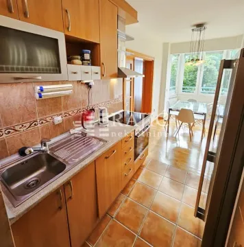 Kitchen with wooden cabinetry and a dining area in the background. - image 4