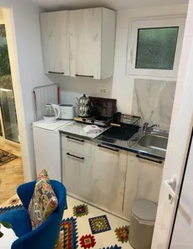 Small kitchenette with white cabinets, sink, and countertop. - image 6