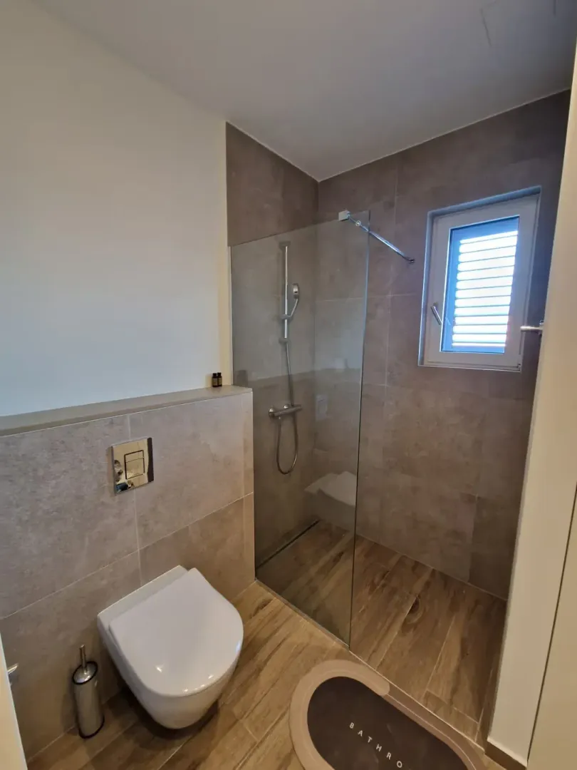 Modern bathroom with a walk-in shower and a built-in toilet.
