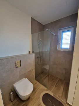 Modern bathroom with a walk-in shower and a built-in toilet. - image 5