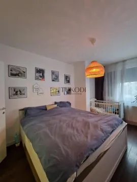 Spavaća soba sa bračnim krevetom, krevetcem i ukrasnim slikama na zidu. - image 15