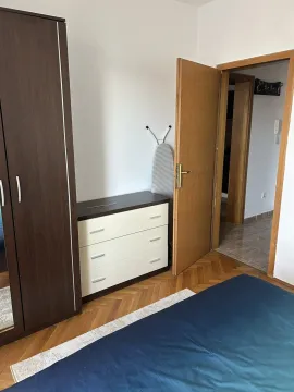 Spavaća soba sa drvenim ormarom, komodom i otvorenim vratima prema hodniku. - image 15
