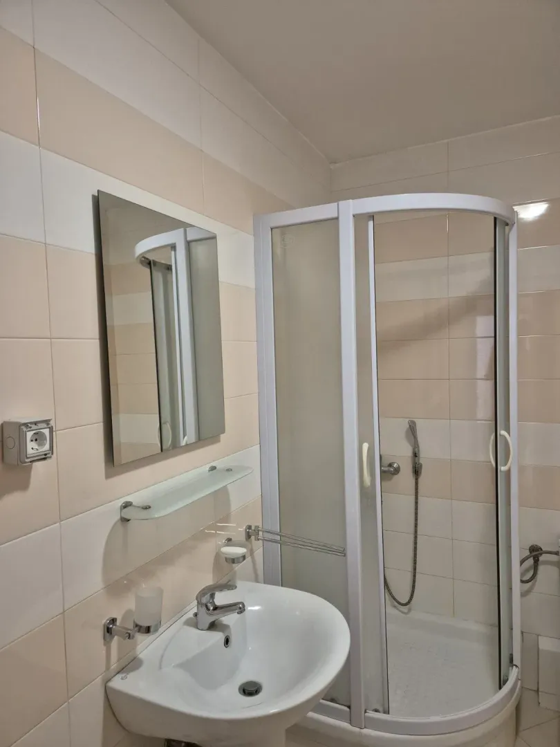 Bright bathroom with a shower cabin and a sink.
