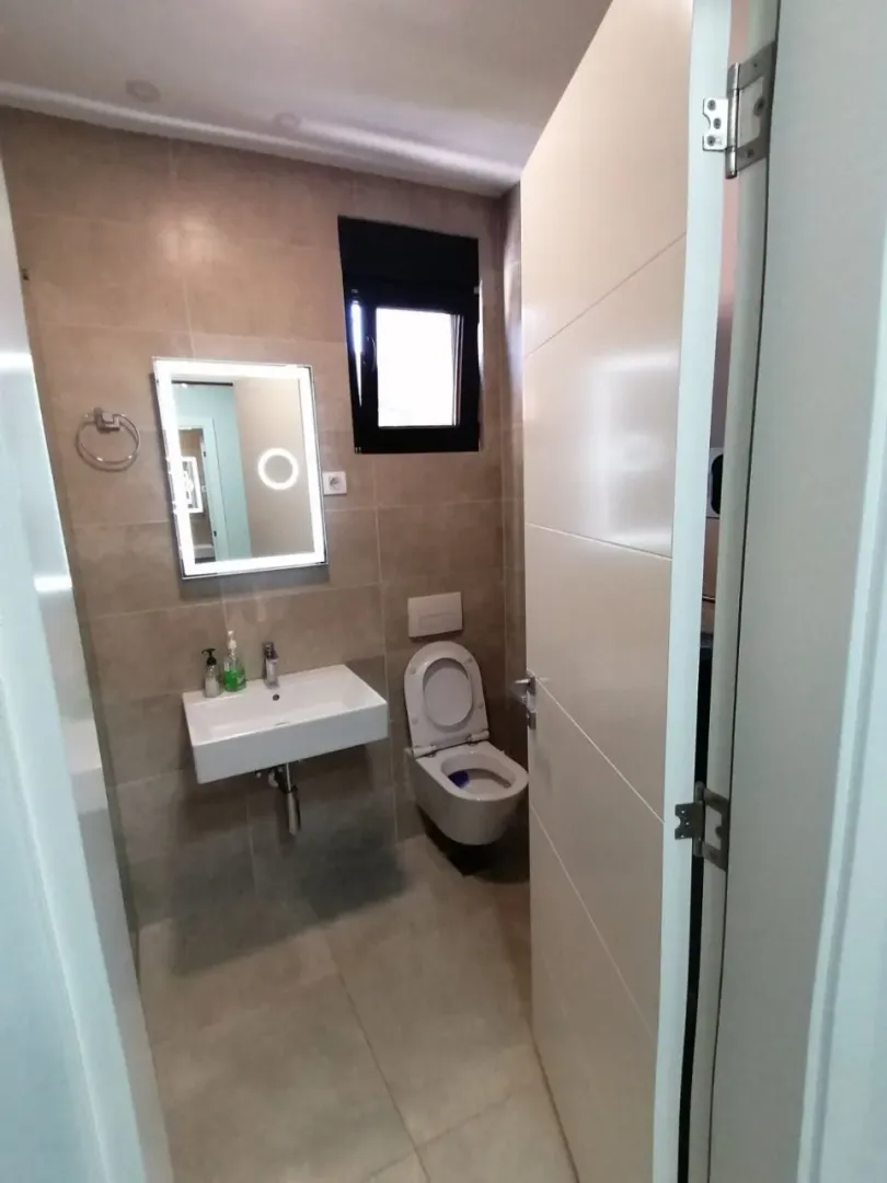 Pogled na moderno uređeno kupatilo sa umivaonikom, ogledalom i wc šoljom.