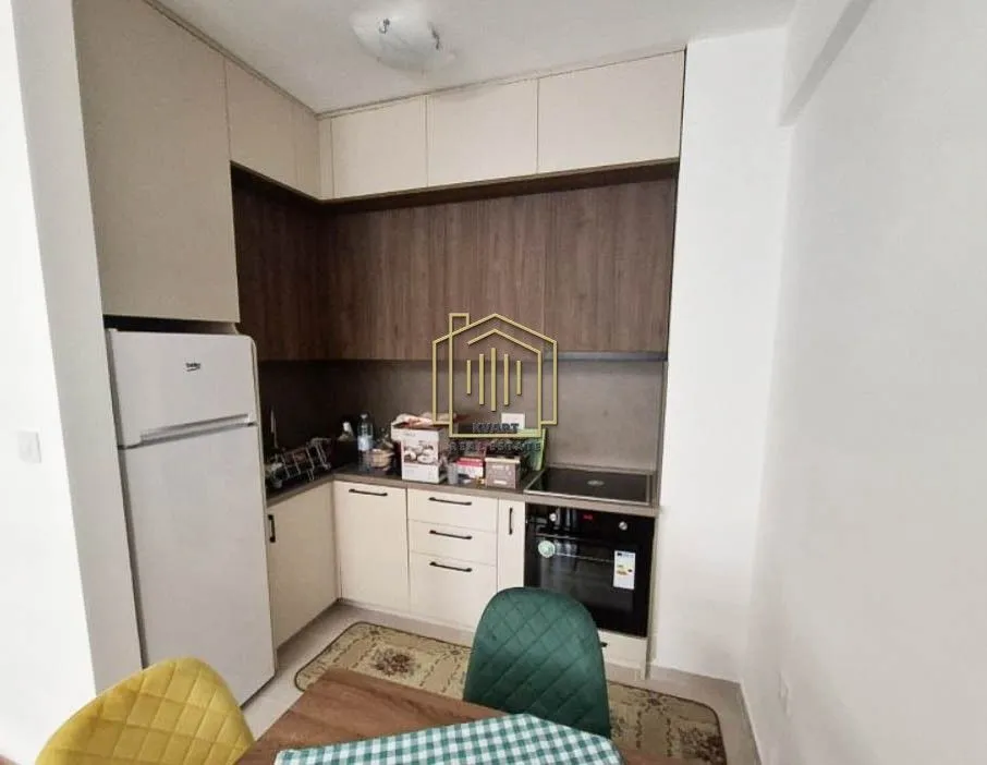 Small kitchen with white and wood-finish cabinets and a refrigerator.