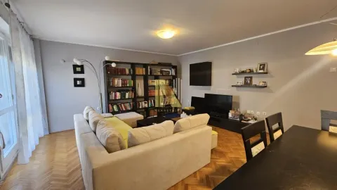 Prostrana dnevna soba sa garniturom za sedenje, televizorom i bibliotekom. - image 3