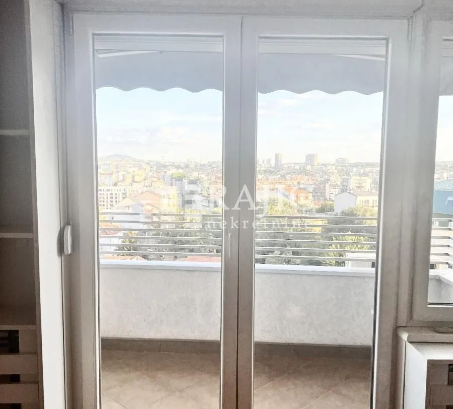 View through balcony doors with a city panorama in the background.