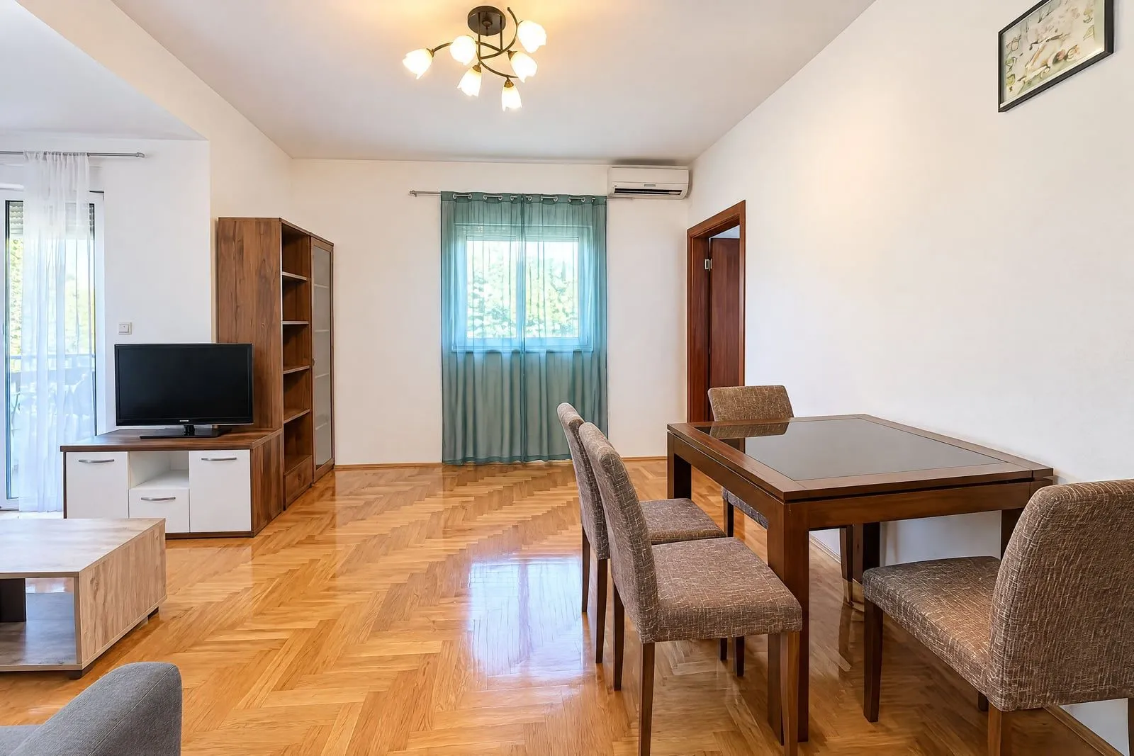Living room with dining area, parquet flooring, and wooden furniture.