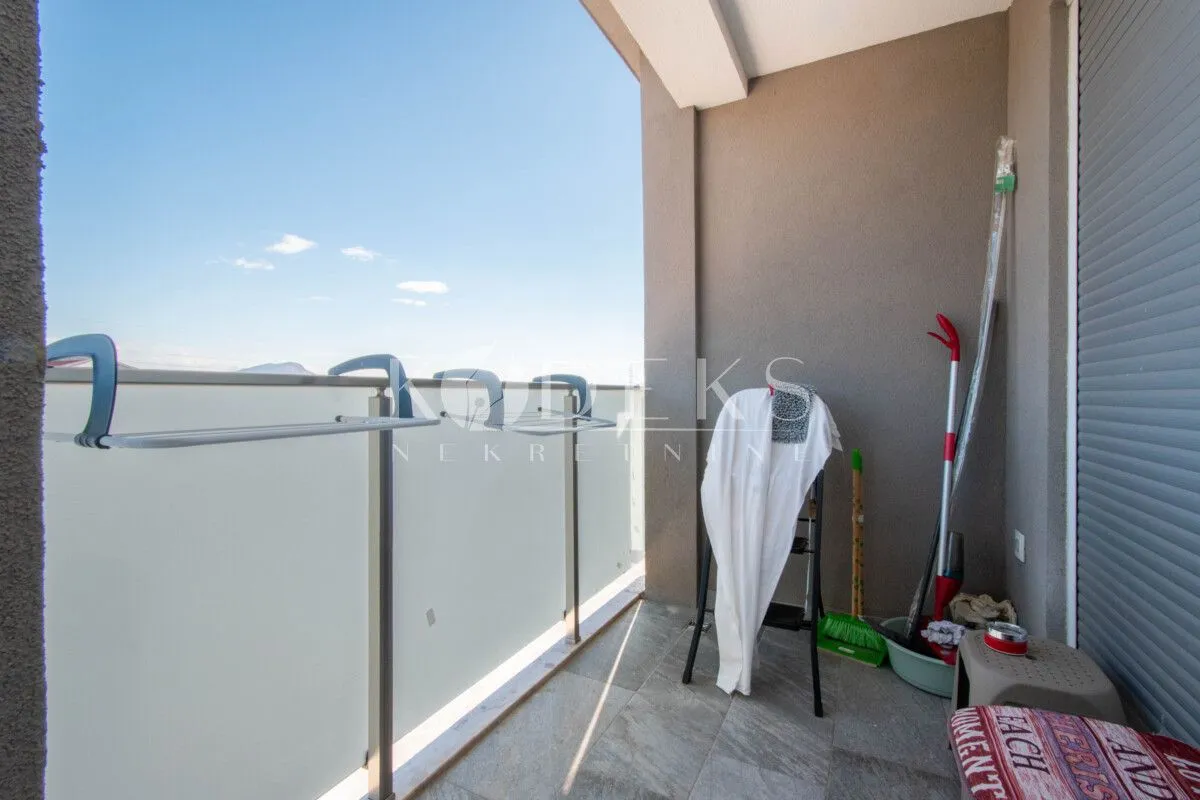 Covered balcony space with cleaning supplies and a clothes drying rack.