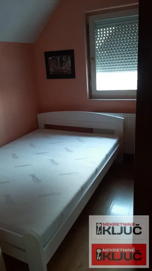 Manja spavaća soba sa belim krevetom i prozorom.