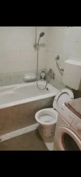 A simple bathroom featuring a bathtub, toilet, and washing machine. - image 5