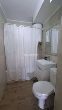 Smaller bathroom with a shower cabin, washbasin, and toilet. - image 12