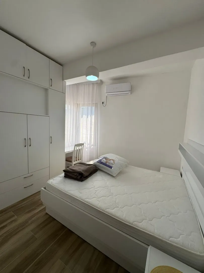Furnished bedroom with a double bed, large wardrobe and air conditioning unit.