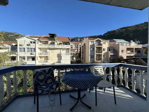 Furnished balcony with a table and chairs and a view of surrounding buildings and hills. - image 5