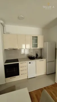 Small kitchen with light cabinetry, built-in appliances, and a refrigerator. - image 4