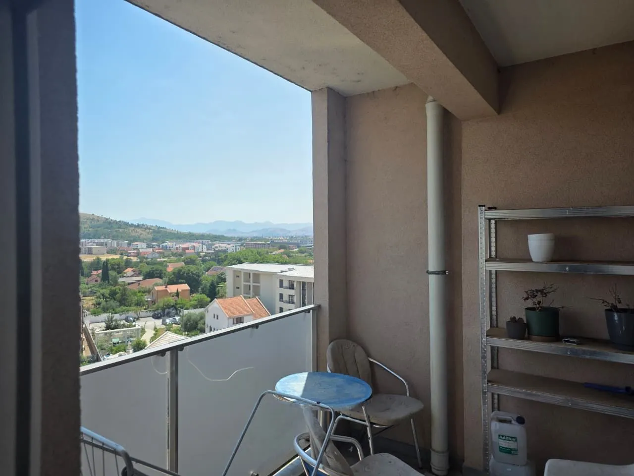 Covered balcony with seating furniture and a city view.