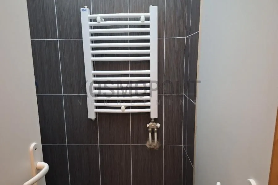 White towel radiator on dark tiles in the bathroom.