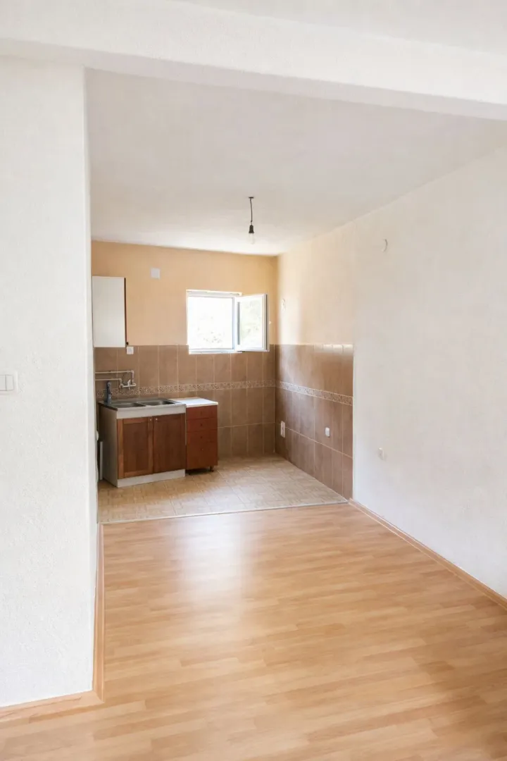 Empty room with installed kitchen units and laminate flooring.