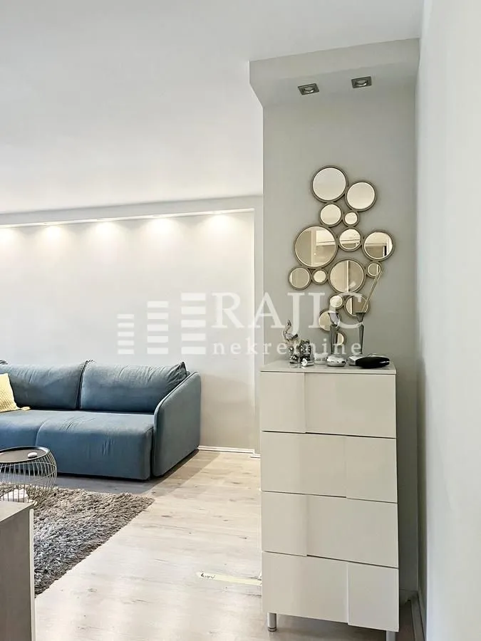 Living room with a sofa, chest of drawers, and wall mirrors.