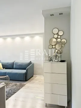 Living room with a sofa, chest of drawers, and wall mirrors. - image 4