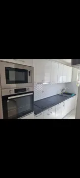 Bright kitchen with built-in appliances and white cabinets. - image 11