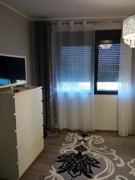 Spavaća soba sa belom komodom, televizorom i prozorom sa zavesama. - image 5