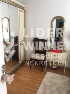 Spavaća soba sa velikim ormanom, ogledalom i stolicom.