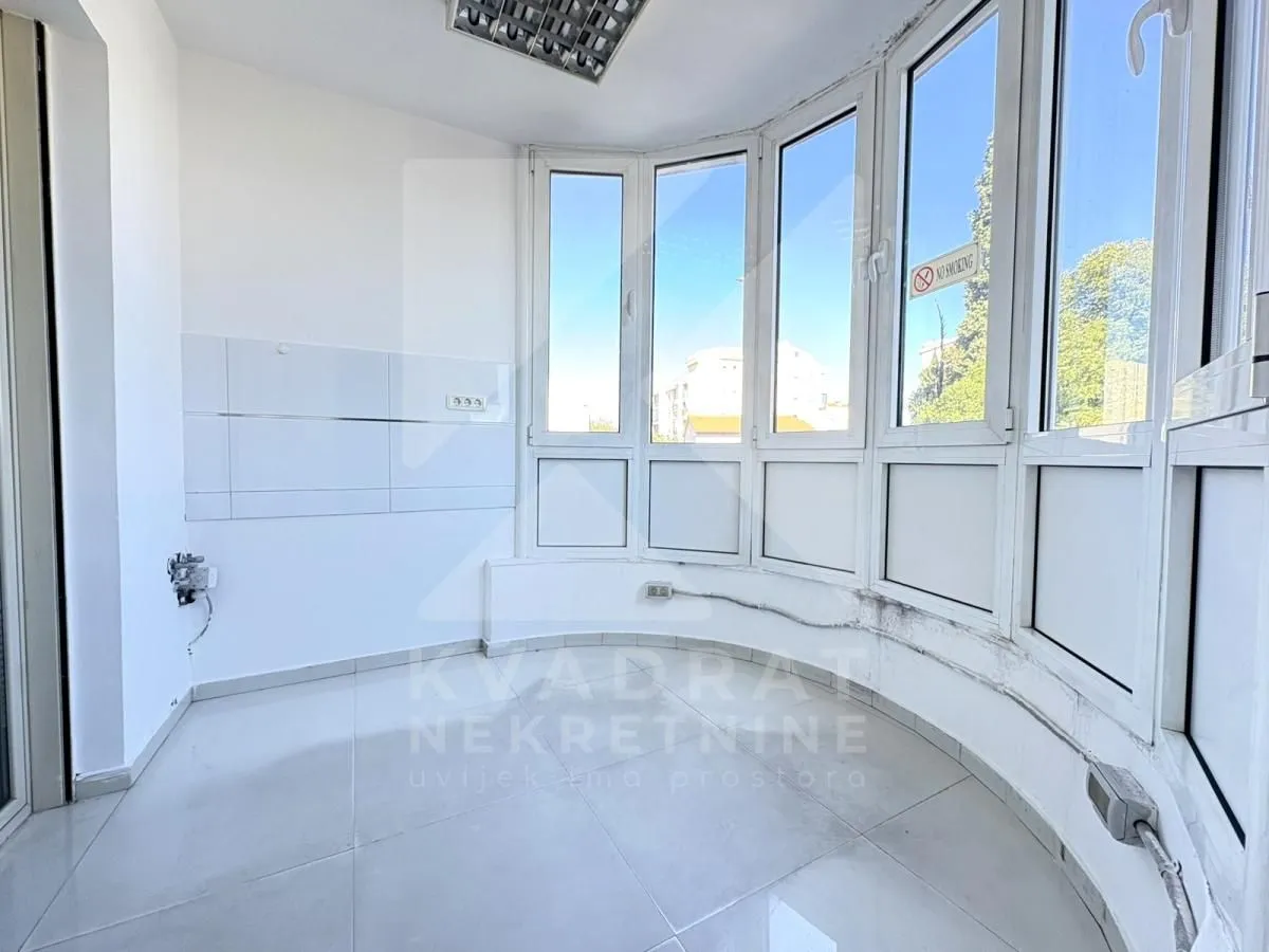 Enclosed balcony with bright walls and tiled flooring.