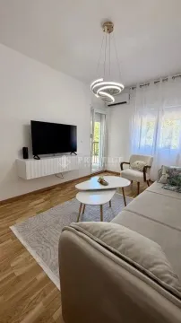 Living room with a sofa, TV, and modern chandelier. - image 3