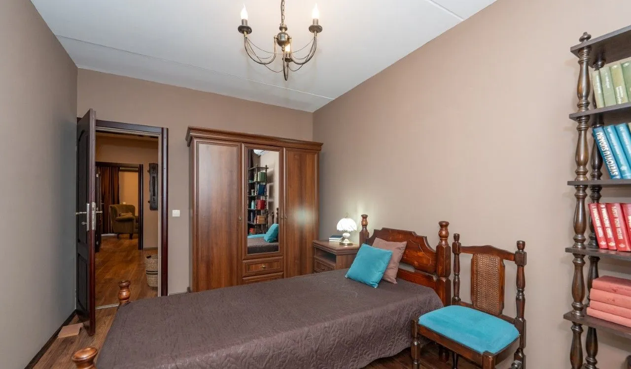 Furnished bedroom with a wooden bed, wardrobe, and bookshelves.