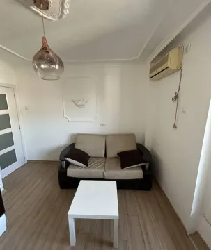Small living room with a two-seater sofa, a coffee table, and an air conditioner. - image 6