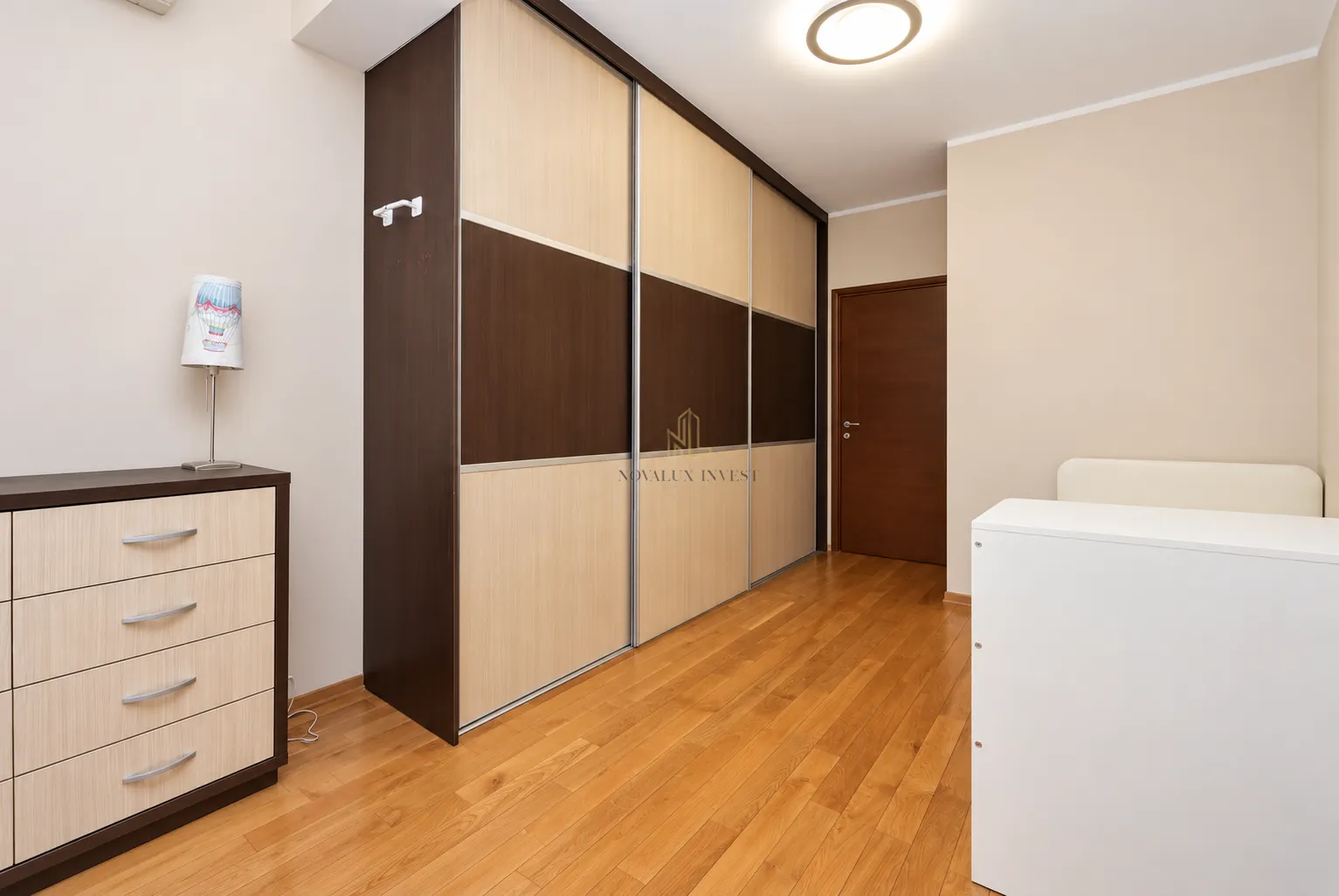 Bedroom with a large built-in wardrobe, chest of drawers, and wooden flooring.